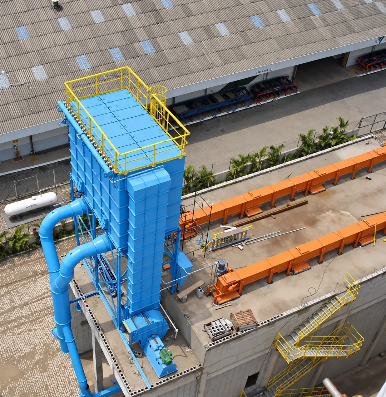 Blue baghouse with yellow platforms, viewed from above at an industrial installation