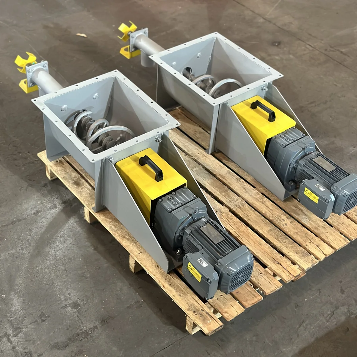 Two units with screw flights, gearmotors, and yellow guards on pallets