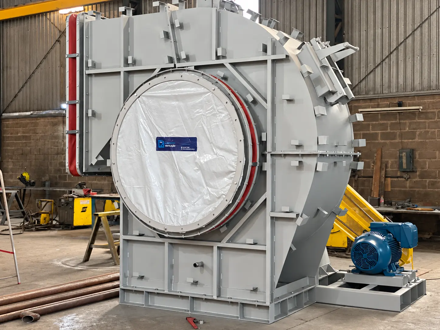 Gray centrifugal fan with a blue motor and yellow guard, photographed at the factory
